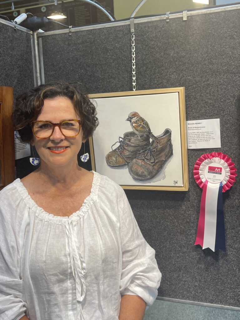 The Dayboro Art Gallery is buzzing with activity. 2 Artist standing beside her winning artwork